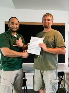 Jeremy Seda receiving a check from Russ Harrington to finalize the fund-raising for Quincy BJJ's mat purchase.